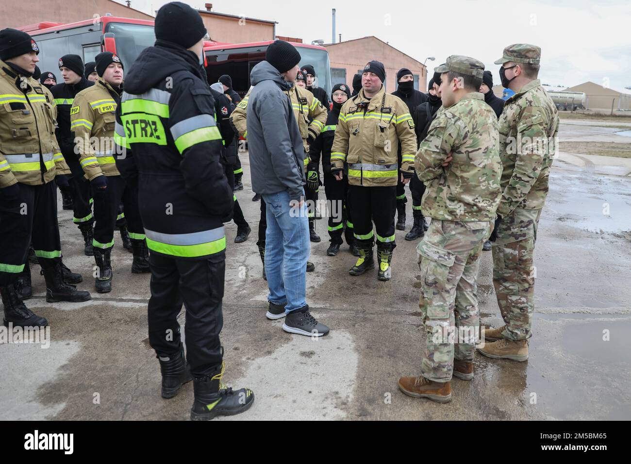 Gregory Skurczynski, linguista del Drawsko Combat Training Center, traduce per soldati e vigili del fuoco polacchi durante una visita guidata a Drawsko Pomorskie, Polonia 23 febbraio 2022. Queste interazioni ampliano l'interoperabilità e la consapevolezza tra i soldati e i servizi di emergenza della nazione ospitante. Foto Stock