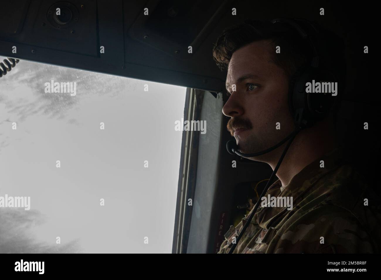 Il primo Lt. James Carignan, pilota di 14th Airlift Squadron, ascolta i piloti comunicare dal posto giusto del membro dell'equipaggio durante un volo locale a North Air Field, North, South Carolina, 24 febbraio 2022. Gli squadroni del sollevatore dell'aria conducono l'addestramento come questi costantemente per mantenere la preparazione. (STATI UNITI Video delle forze aeree dello staff Sgt. Christian Sullivan) Foto Stock
