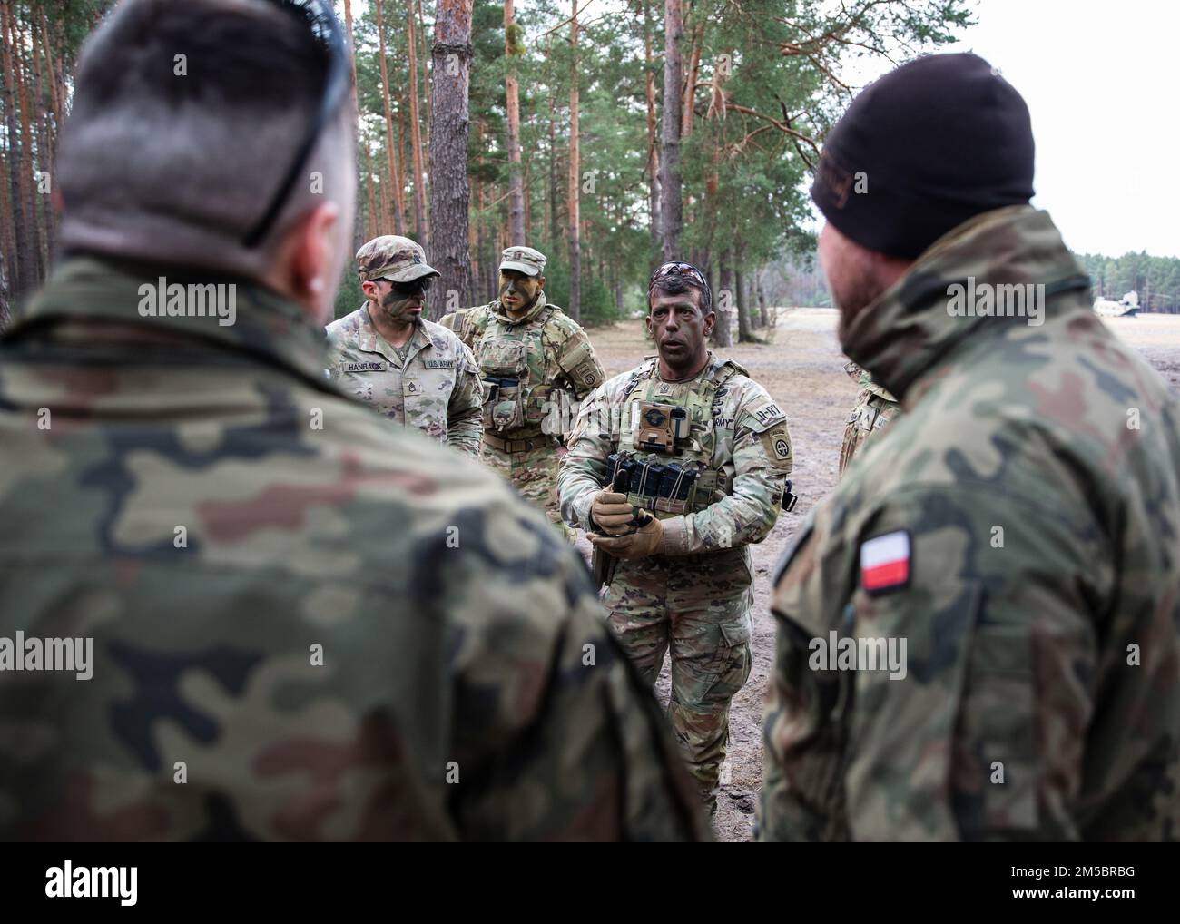 Primo sergente degli Stati Uniti assegnato a 3rd Brigade Combat Team, 82nd Airborne Division fornisce la direzione ai suoi paracadutisti e soldati polacchi assegnati alla 21st Rifle Brigade durante un evento di addestramento combinato a Nowa Deba, Polonia, 25 febbraio 2022. L'obiettivo della missione della 82nd Airborne Division è quello di assicurare i nostri alleati e dissuadere l'aggressione fornendo una serie di capacità uniche e conducendo un'ampia gamma di missioni scalabili e adattabili alle esigenze della missione. Foto Stock