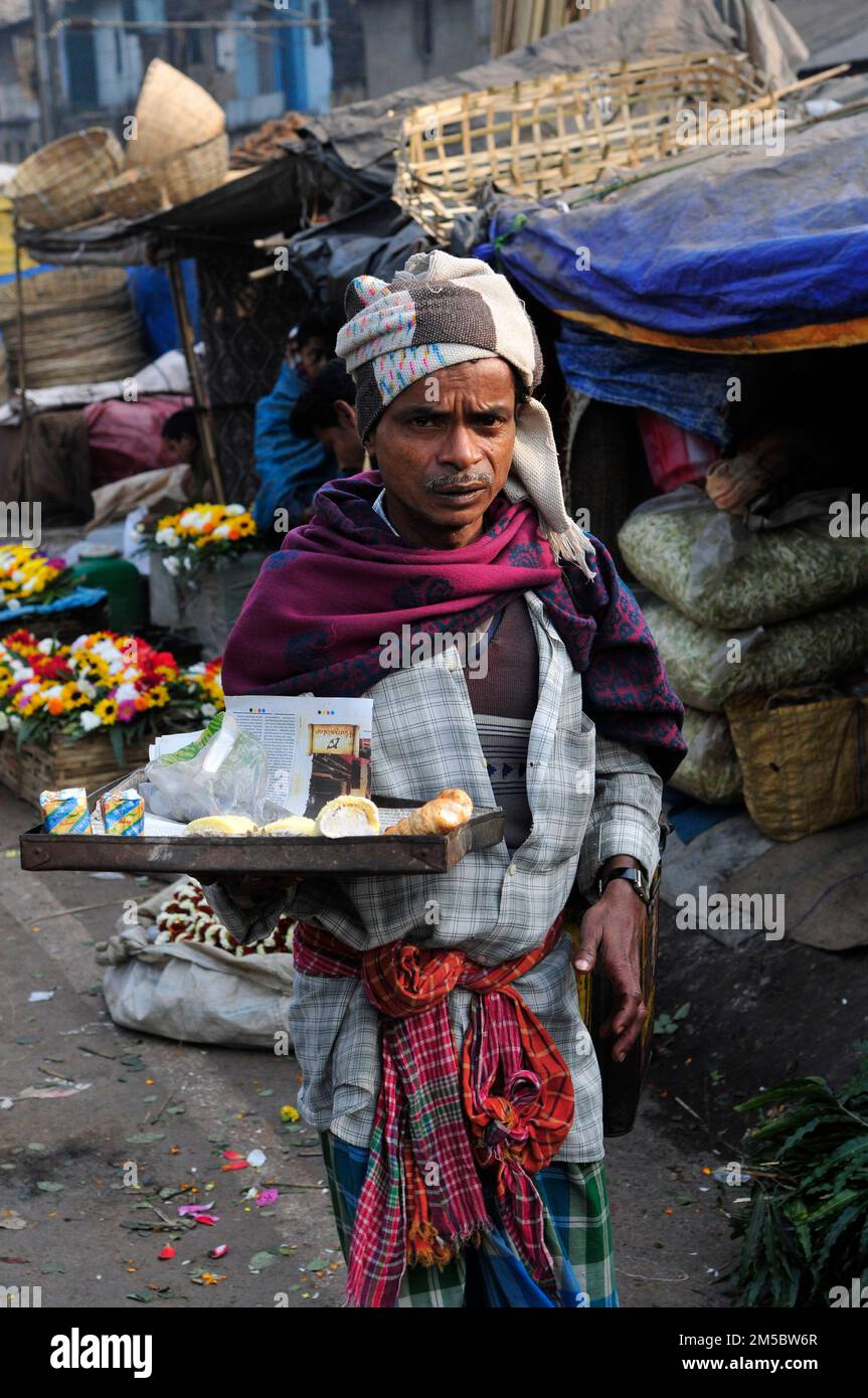 Un uomo bengalese che vende sbuffi di crema al mercato dei fiori a Mallick Ghat a Kolkata, India. Foto Stock