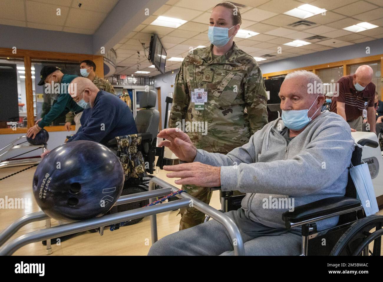 STATI UNITI Kara Kauffman, Maintenance Squadron, 177th Fighter Wing, New Jersey Air National Guard, guarda Fred Malone Jr., residente presso la New Jersey Veterans Memorial Home di Vineland, spinge una palla da bowling giù per una rampa presso la pista da bowling Home di Vineland, New Jersey, 24 febbraio, 2022. Kauffman sta servendo i residenti della Casa nel Dipartimento di arricchimento della vita. Più di 70 soldati della Guardia Nazionale del New Jersey e Airmen stanno servendo come assistenti infermieristici certificati e in servizi alimentari, controllo delle infezioni, tecnologia dell'informazione, arricchimento della vita, Logistica, E COVID-19 testi Foto Stock