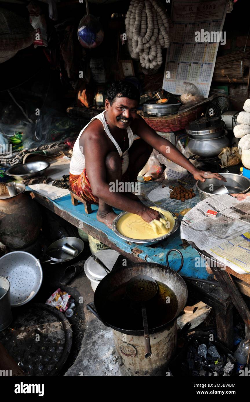 Un uomo bengalese friggere il pane in un piccolo ristorante a Kolkata, India. Foto Stock