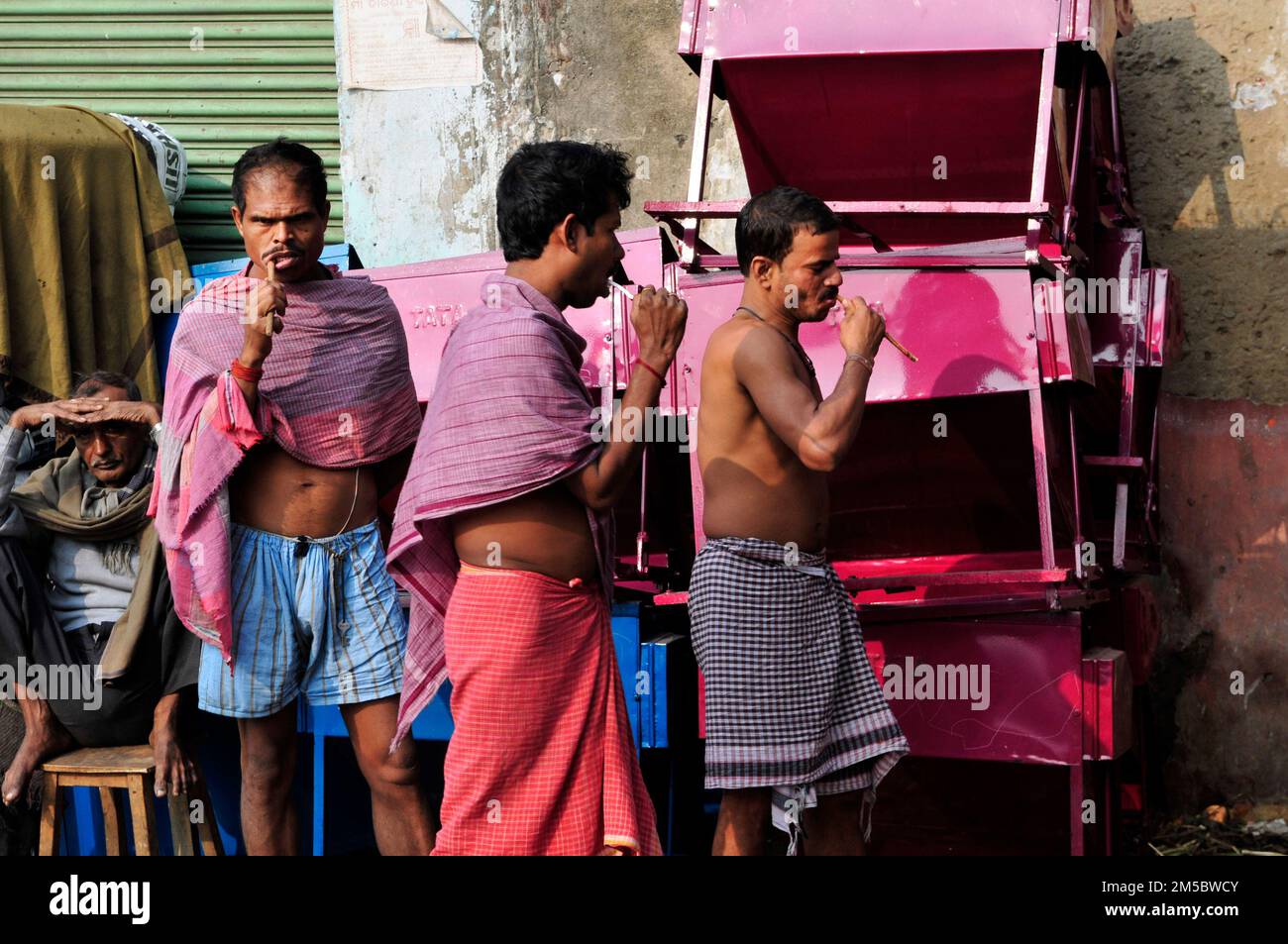 Uomini bengalesi spazzolano i denti con uno spazzolino tradizionale. Kolkata, India. Foto Stock