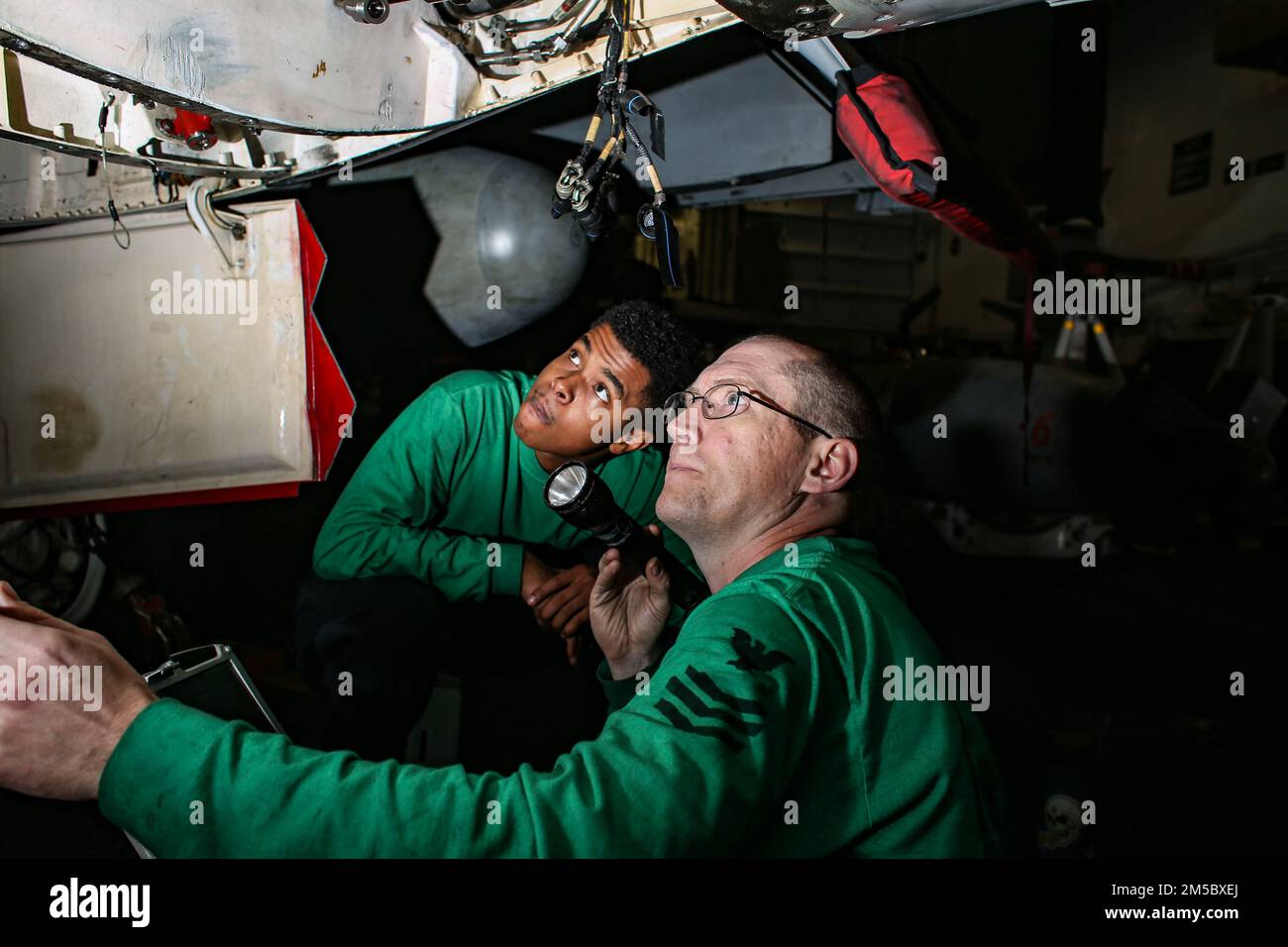 MARE DELLE FILIPPINE (25 febbraio 2022) Aviation Electrician’s Mate 3rd Class Jestin Lewis, a sinistra, da Los Angeles, E il compagno di classe 1st dell'Aviation Electrician Brian Liesse, di Stoughton, Wisconsin., effettua un controllo della cavità su un EA-18G Growler, assegnato ai 'Wizards' di Electronic Attack Squadron (VAQ) 133, nella baia dell'hangar a bordo della portaerei di classe Nimitz USS Abraham Lincoln (CVN 72). Abraham Lincoln Strike Group è in fase di implementazione pianificata nell'area delle operazioni della flotta 7th degli Stati Uniti per migliorare l'interoperabilità attraverso alleanze e partnership e al contempo fungere da forza di pronto intervento a supporto di o Foto Stock