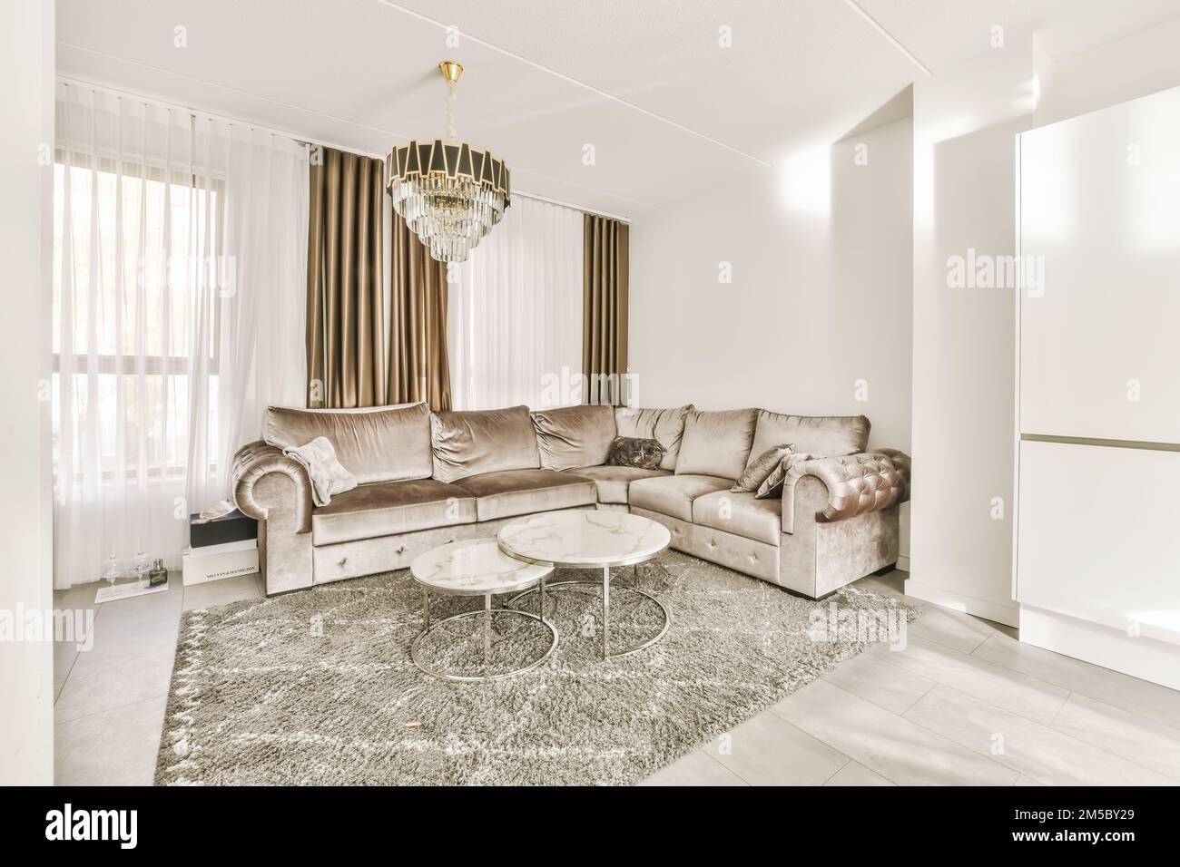 un soggiorno con divano, tavolino da caffè e chandels sulla parete della camera è molto bianco Foto Stock