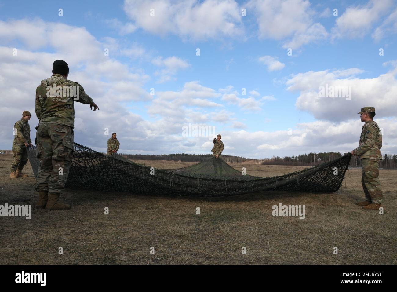 STATI UNITI Soldati dell'esercito assegnato a 5th battaglione, 4th Air Defense Artillery Regiment, piega mimetizzazione durante l'esercizio sciopero Saber presso Bemowo Piskie Training Area, Polonia, 25 febbraio 2022. La serie di esercizi Saber Strike è stata condotta regolarmente dal 2010 e ha avuto grande successo sia nel migliorare l'interoperabilità tra alleati e partner della NATO sia nel migliorare la capacità operativa congiunta in una varietà di gruppi di missioni. Foto Stock