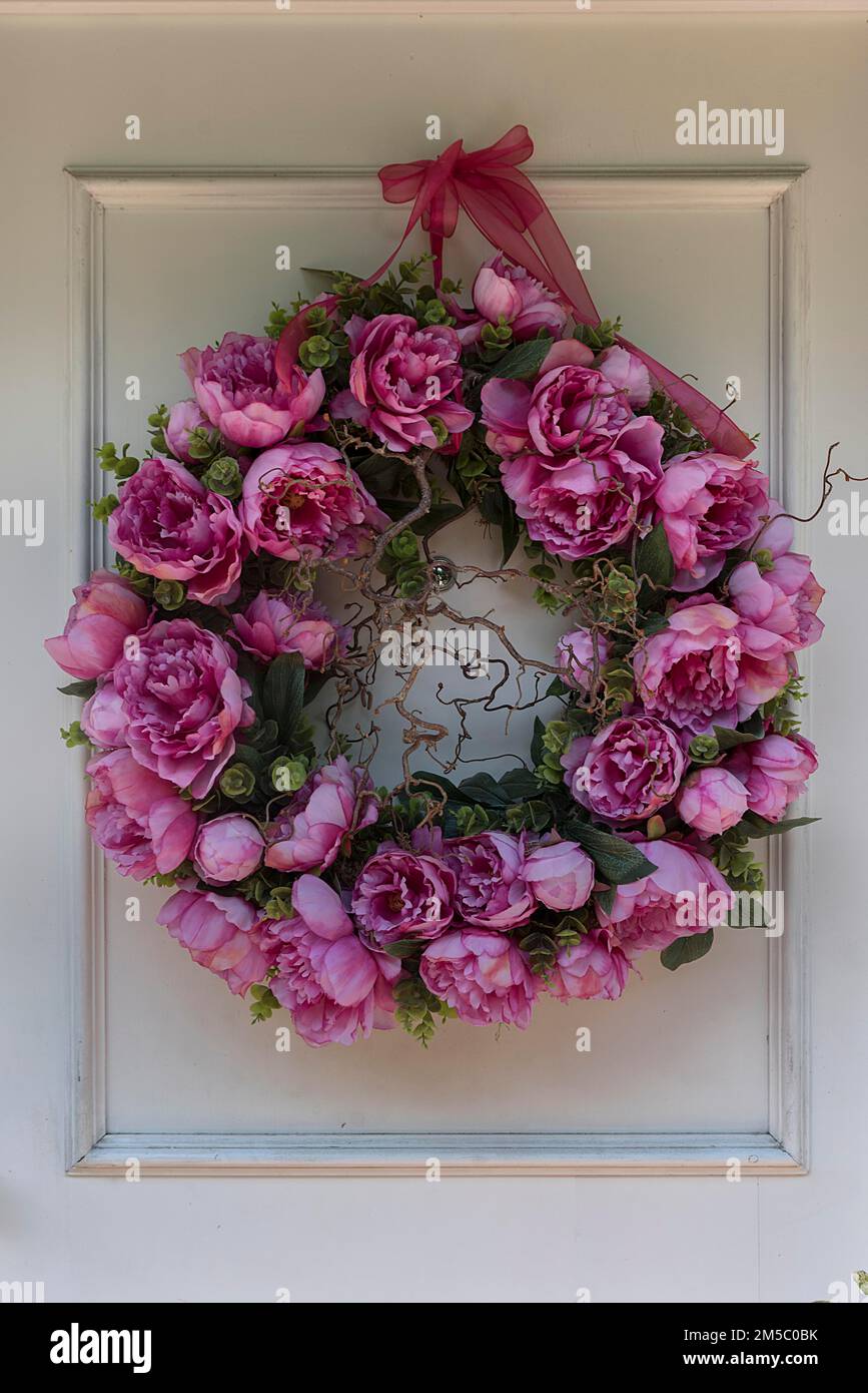 Corona di fiori artificiali con fiori di peonia (Paeonia), su una porta d'ingresso, Baviera, Germania Foto Stock