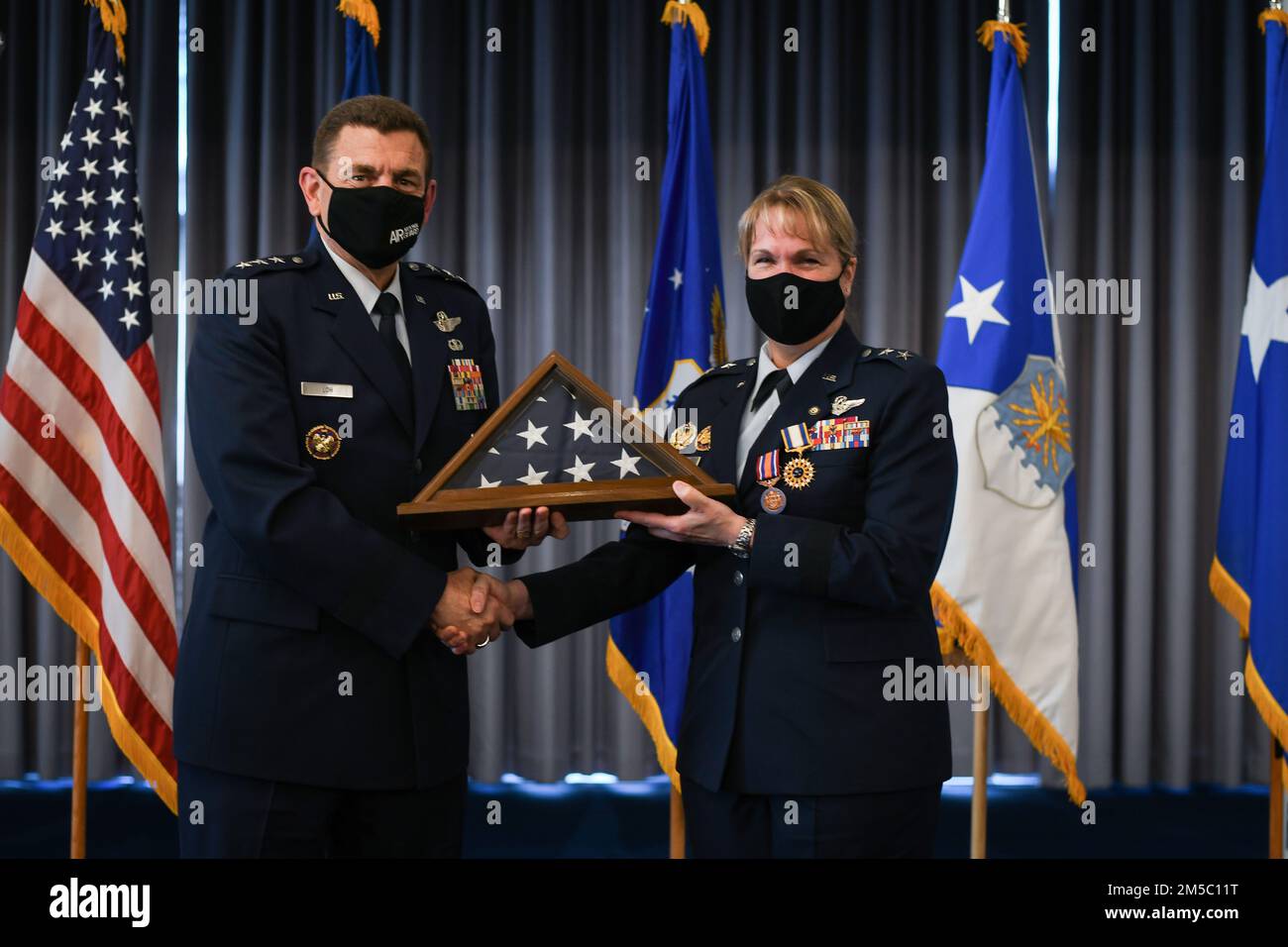 STATI UNITI Michael A. Loh, direttore della Guardia Nazionale aerea, presenta una bandiera americana al vice direttore generale Dawne Deskins, Air National Guard, durante la cerimonia di ritiro presso la base congiunta Anacostia-Bolling, District of Columbia, 25 febbraio 2022. Deskins si ritirò dopo 37 anni di servizio militare nell'Aeronautica militare e nella Guardia Nazionale aerea. Foto Stock