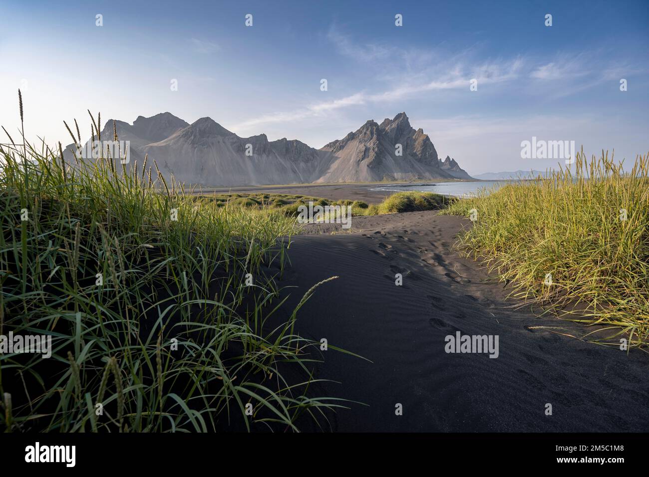 Spiaggia nera con sabbia vulcanica, spiaggia sabbiosa, dune con erba, promontorio di Stokksnes, catena montuosa di Clifatindur, Austurland, Islanda orientale, Islanda Foto Stock