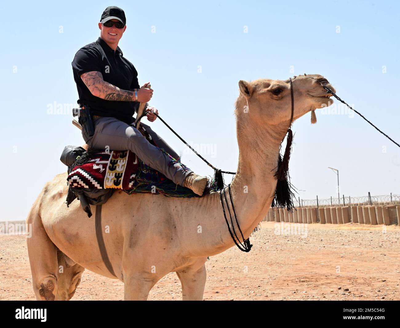 STATI UNITI Air Force Airman 1st Class Brian Schmidt, 409th membro dello Squadrone delle forze di sicurezza espeditionarie, cavalca un cammello durante un bazar alla base aerea nigeriana 201, Agadez, Niger, 27 febbraio 2022. Oltre 40 venditori locali dalla città di Agadez e villaggi circostanti hanno frequentato il bazar, vendendo vari beni. I membri del servizio negli Stati Uniti hanno acquistato circa 10.532.000 franchi CFA dell'Africa occidentale ($18K USD) di merci. Eventi come questi migliorano le relazioni tra Stati Uniti e Niger e stimolano lo sviluppo economico locale. Foto Stock