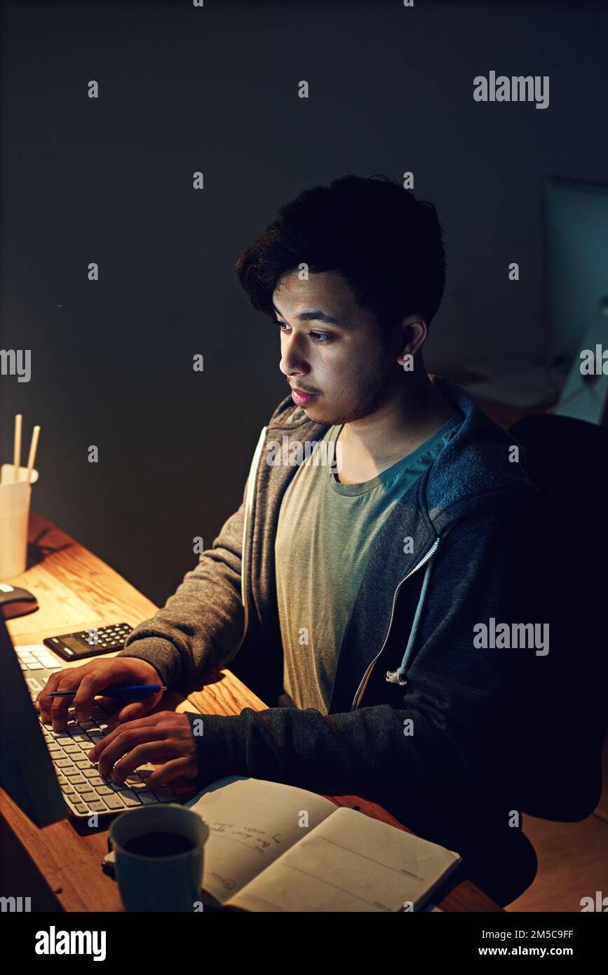 Non gli importa lavorare autonomamente. un designer che lavora al suo computer per un turno di notte al lavoro. Foto Stock