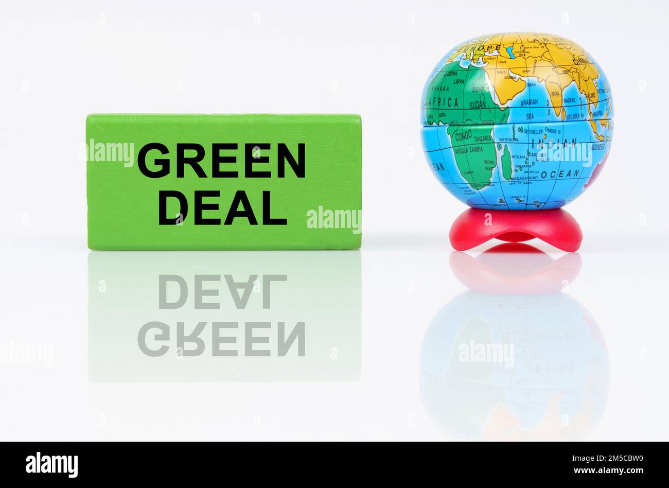 Concetto ecologico. Su una superficie riflettente è un globo e un segno verde con l'iscrizione - Green Deal Foto Stock