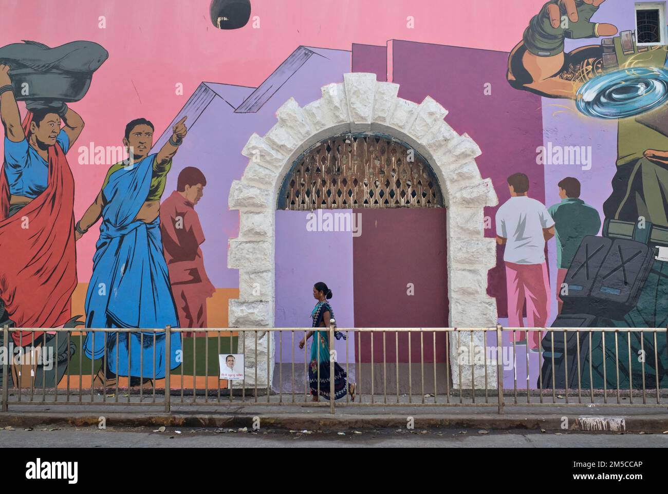 Una donna passa un dipinto a parete colorato a Sassoon Docks, Colaba, Mumbai, India Foto Stock