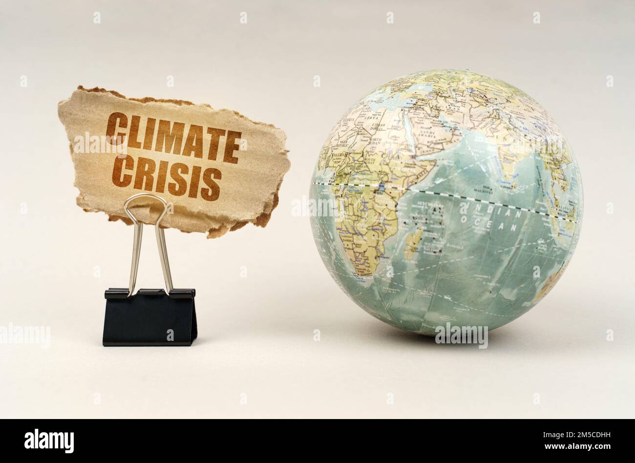 Concetto ecologico. Vicino al globo c'è una clip con una piastra di cartone su cui è scritto - crisi climatica Foto Stock