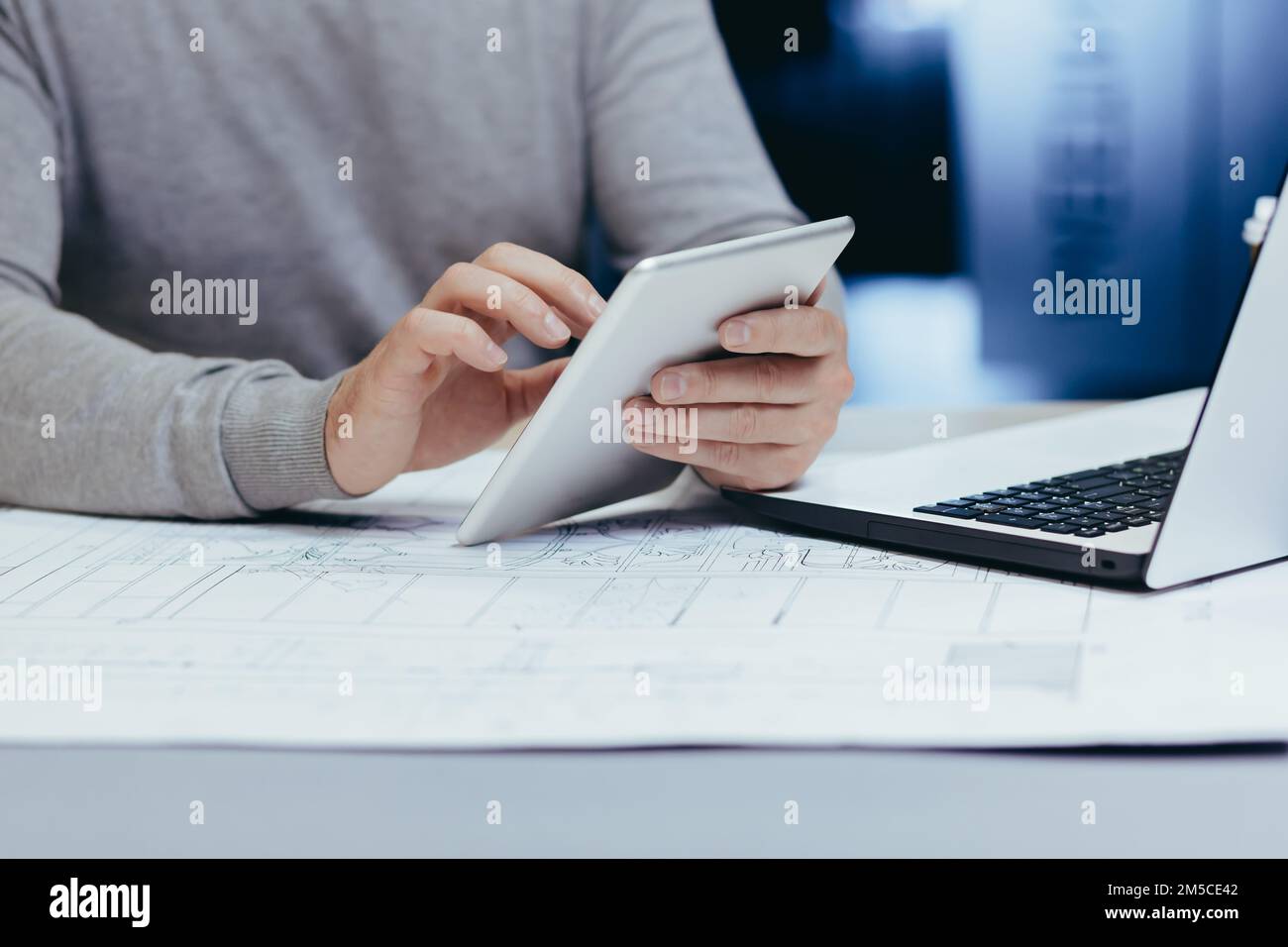 Foto ravvicinata delle mani di un architetto designer maschile che lavora con un tablet all'interno di un ufficio moderno. Foto Stock