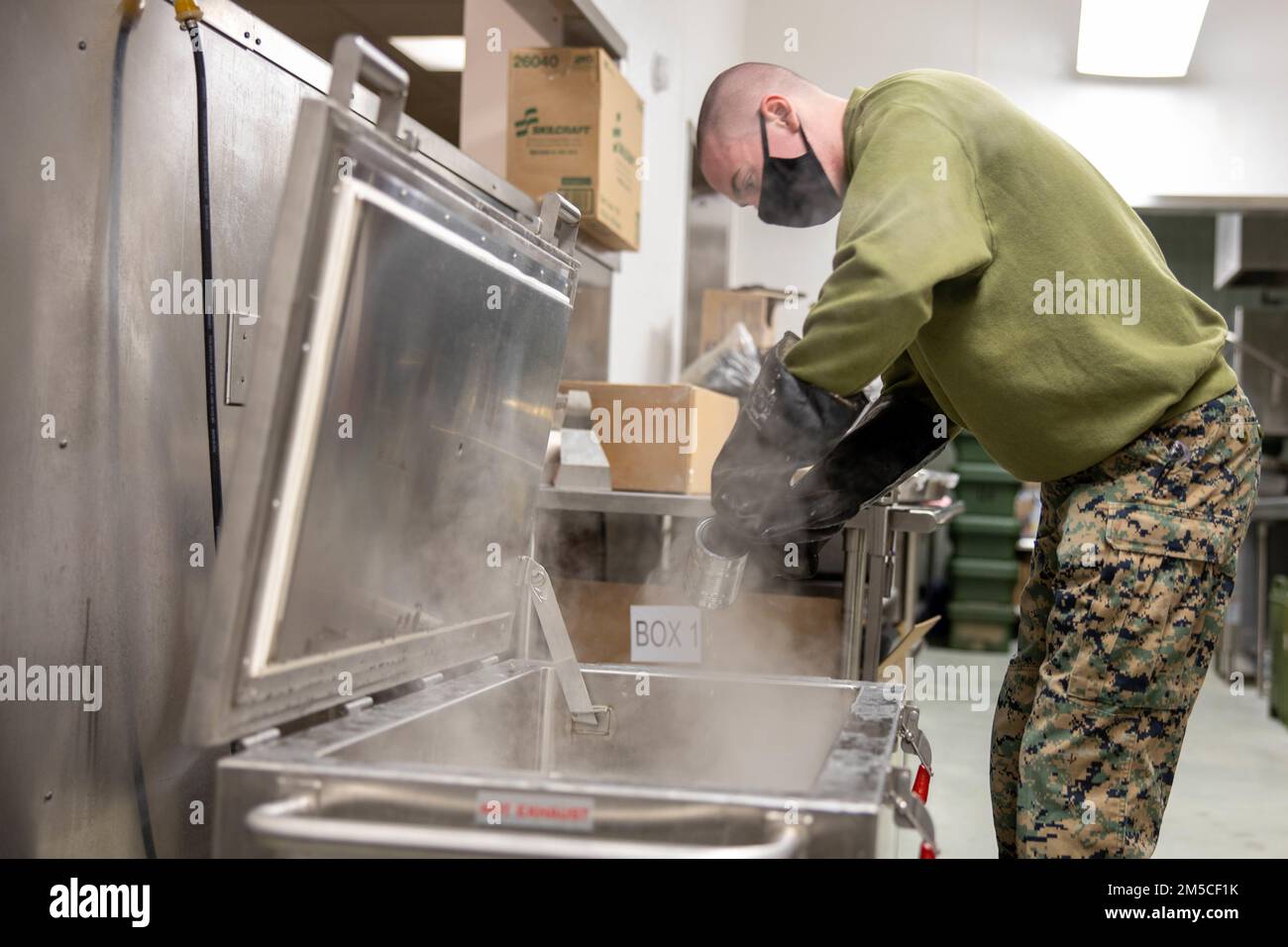 STATI UNITI Connor Young, uno specialista di cibo con 2nd Battaglione di supporto all'atterraggio, estrae lattine di pancetta da un sistema di riscaldamento a vassoio, presso l'Aurora Event Center sulla base dell'aeronautica militare di Eielson, Fairbanks, Alaska, 1 marzo 2022. 2nd LSB fornisce un ruolo di supporto critico durante l'esercitazione Arctic Edge 22, fornendo servizi alimentari per gli Stati Uniti Soldati dell'esercito che partecipano all'addestramento di tempo freddo. Foto Stock