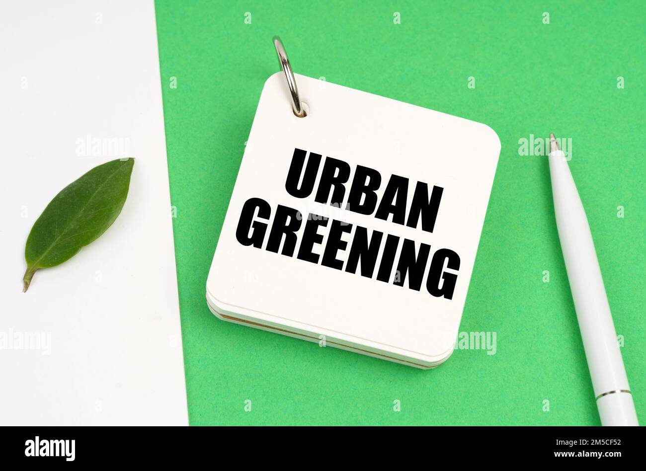 Concetto ecologico. Su una superficie bianco-verde, un pezzo di carta, una penna e un blocco note con il testo - verde urbano Foto Stock