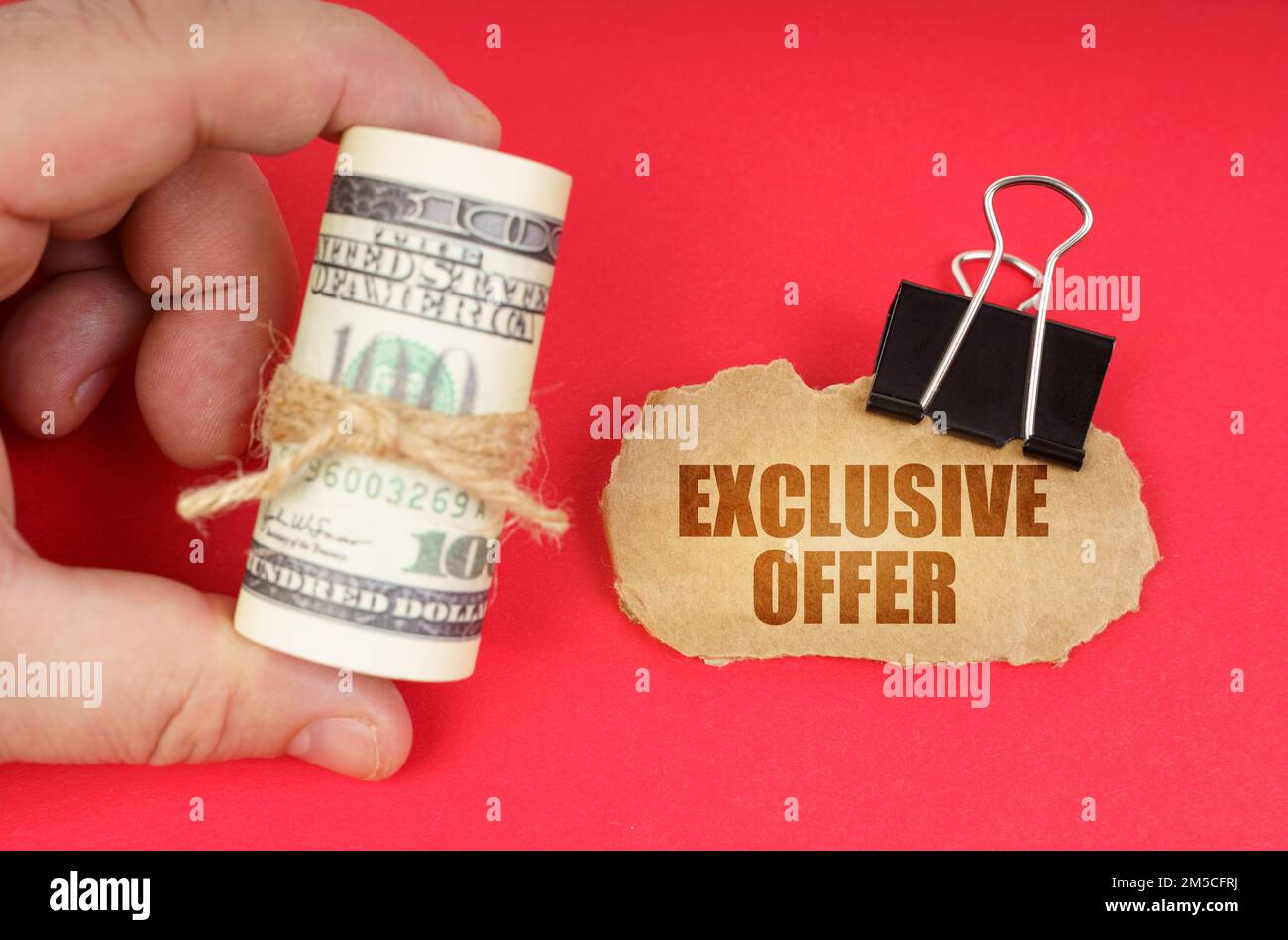 Concetto aziendale. L'uomo ha dei dollari nelle sue mani, su una superficie rossa c'è un cartoncino con l'iscrizione - Offerta esclusiva Foto Stock
