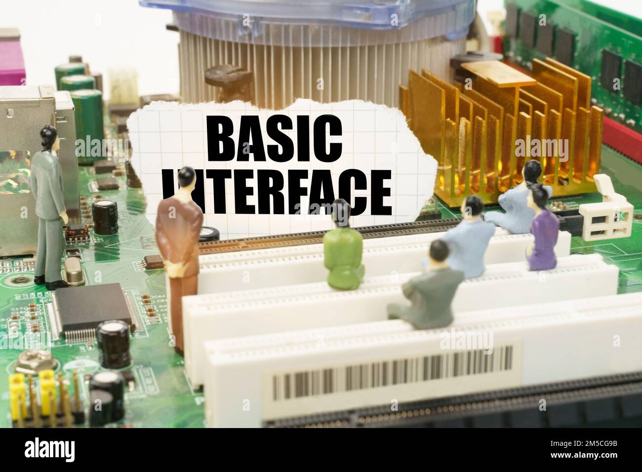 Tecnologia e concetto informatico. Sulla scheda madre ci sono figure di persone e carta strappata con l'iscrizione - Basic Interface Foto Stock