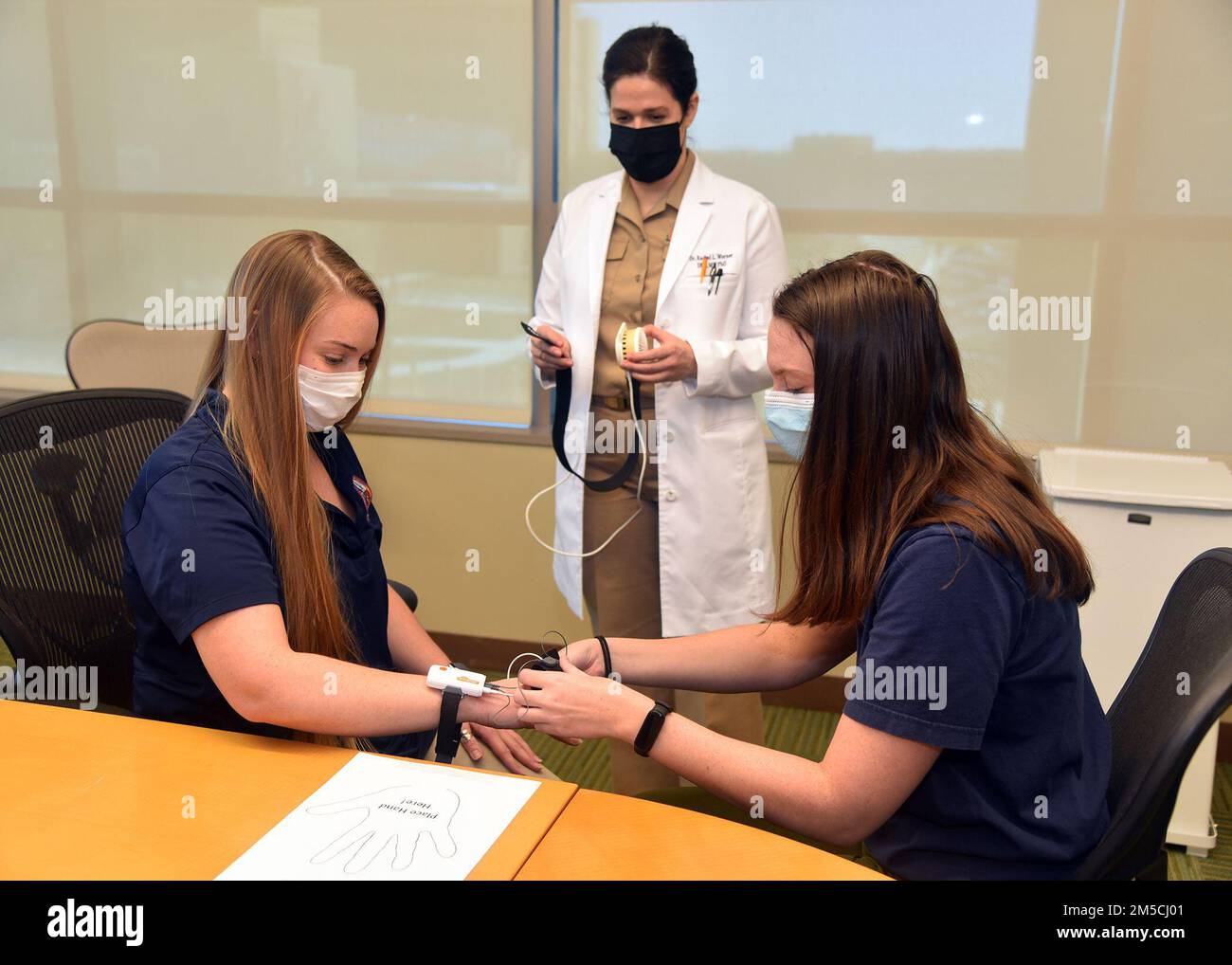 BASE COMUNE SAN ANTONIO-FORT SAM HOUSTON – (1 marzo 2022) Stephanie Speaker (a destra), di West Warwick, R.I., un ingegnere biomedico del Naval Undersea Warfare Center, conduce un test di pratica per il rilevamento dell'attività elettrodermica per il rilevamento quantitativo del dolore su Katie Geary, di Belcamp, M., Un ingegnere di ricerca con Naval Medical Research Unit (NAMRU) San Antonio presso il Battlefield Health and Trauma Building 2 situato vicino al Brooke Army Medical Center mentre CMdR. Rachel Werner, di Cocoa Beach, Fla., capo del Maxillofacial Injury and Disease Department di NAMRU San Antonio, osserva Foto Stock