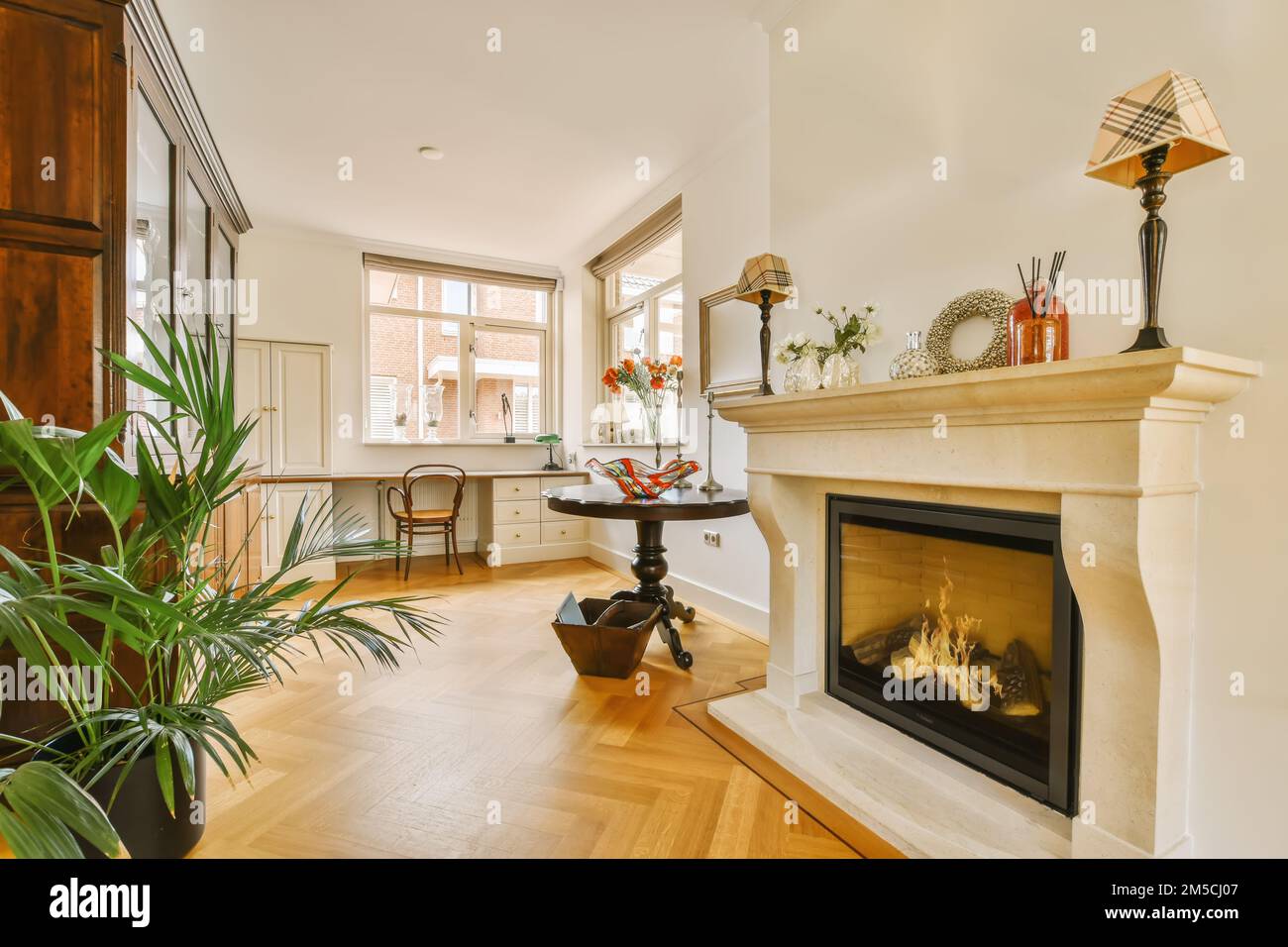un soggiorno con pavimenti in legno e un camino al centro della stanza, vi è un camino Foto Stock