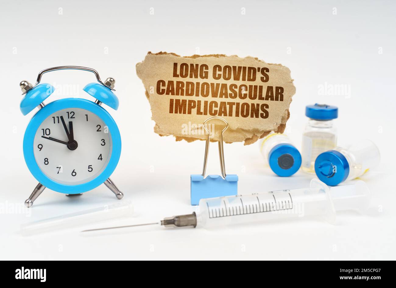 Concetto medico. Vicino allo stetoscopio ci sono una siringa, fiale e una clip con una piastra di cartone - COVID lunghi implicazioni cardiovascolari Foto Stock