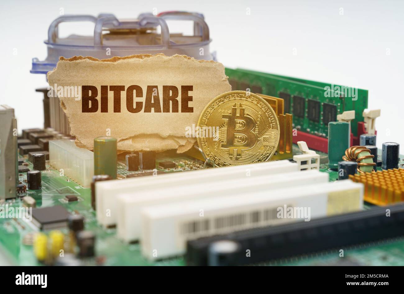 Crypto - concetto di business. Sulla scheda madre si trova una moneta bitcoin e un cartoncino con l'iscrizione - Bitcare Foto Stock