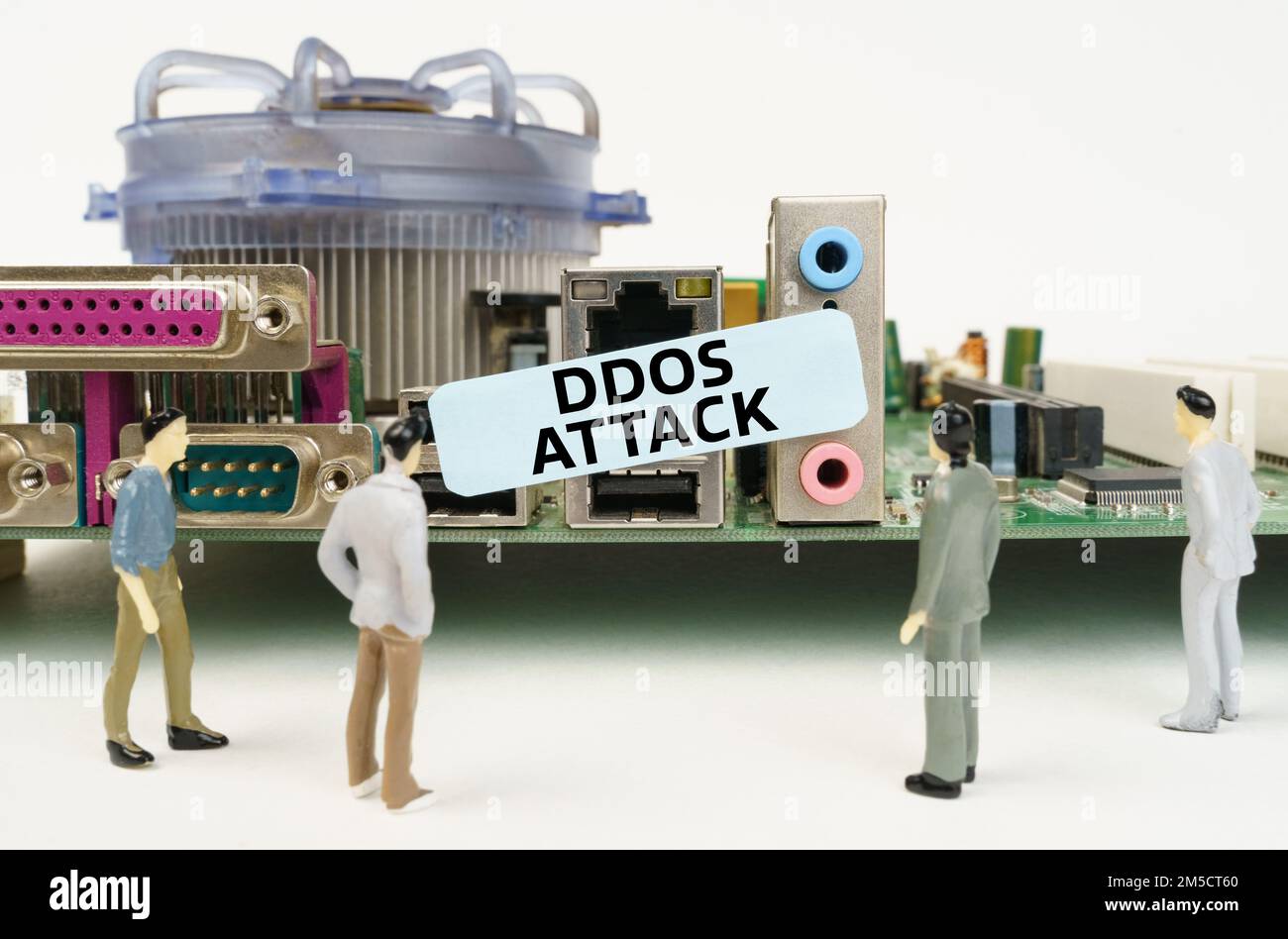 Tecnologia e concetto informatico. Figure di persone sono in piedi vicino alla scheda madre e guardando l'adesivo con l'iscrizione - attacco DDoS Foto Stock