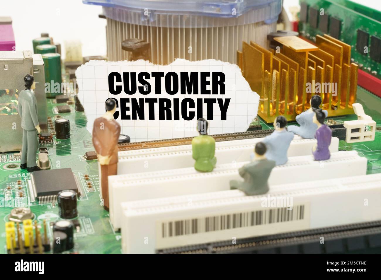 Tecnologia e concetto informatico. Sulla scheda madre ci sono figure di persone e carta strappata con l'iscrizione - customer centricity Foto Stock