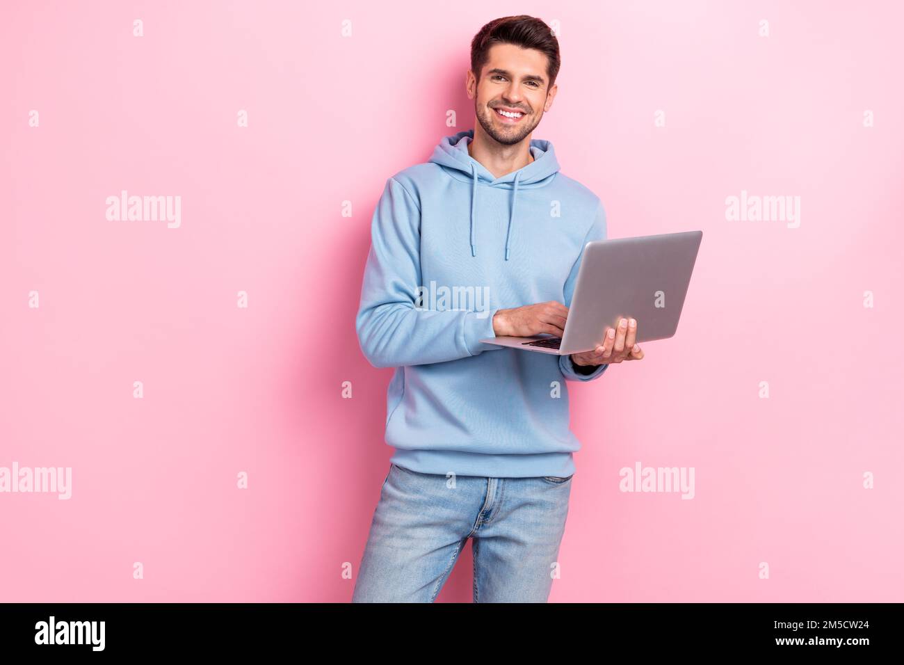 Foto di un ragazzo abbastanza positivo vestito felpa blu lavoro mela samsung gadget spazio vuoto isolato sfondo di colore rosa Foto Stock