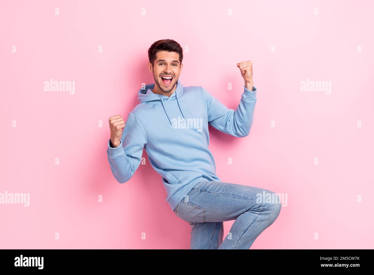 Foto di buon umore ragazzo fortunato vestito blu felpa che si innalza pugni  urlando isolato sfondo di colore rosa Foto stock - Alamy