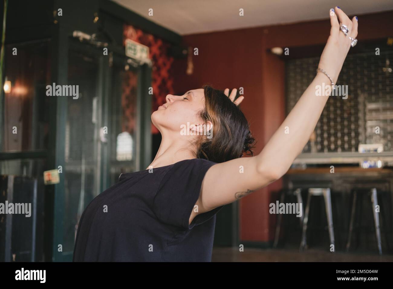 Foto laterale di una donna yoga che fa una posa sul retro con le braccia aperte durante la pratica di yoga con flusso di vinyasa Foto Stock