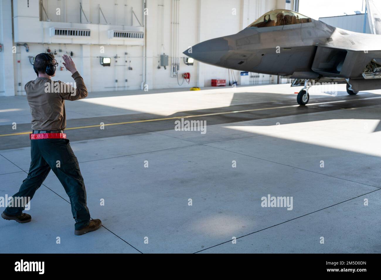 STATI UNITI Tecnologia Air Force. SGT. Zachary Walters, un capo dell'equipaggio dell'unità di manutenzione degli aeromobili del 90th, marshalls un F-22 Raptor presso la Joint base Elmendorf-Richardson, Alaska, 2 marzo 2022. Il F-22 Raptor è il primo aereo da combattimento della quinta generazione dell'aeronautica militare. La sua combinazione di furtività, supercrociera, estrema manovrabilità e avionica integrata rappresenta un salto nelle capacità di combattimento in guerra. Foto Stock