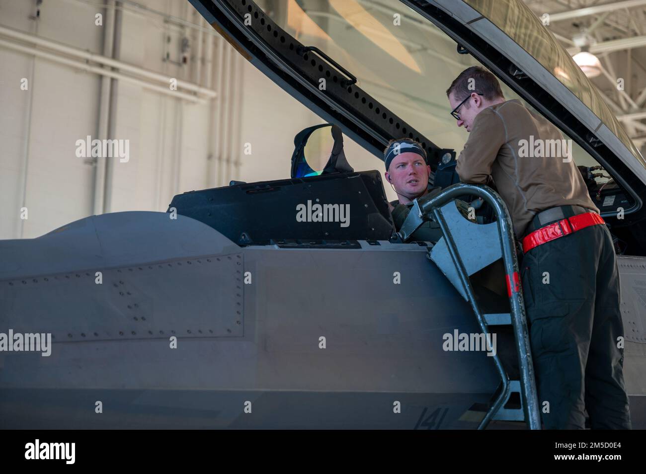 STATI UNITI Tecnologia Air Force. Zachary Walters, un capo dell'equipaggio della 90th Aircraft Maintenance Unit, parla con gli Stati Uniti Nathan Johnson, un pilota di caccia 90th Fighter Squadron, dopo un addestramento alla base militare Elmendorf-Richardson, Alaska, 2 marzo 2022. Il sofisticato aerodesign F-22, i controlli di volo avanzati, la vettorizzazione della spinta e l'elevato rapporto spinta-peso offrono la capacità di superare tutti gli aerei presenti e proiettati. Foto Stock