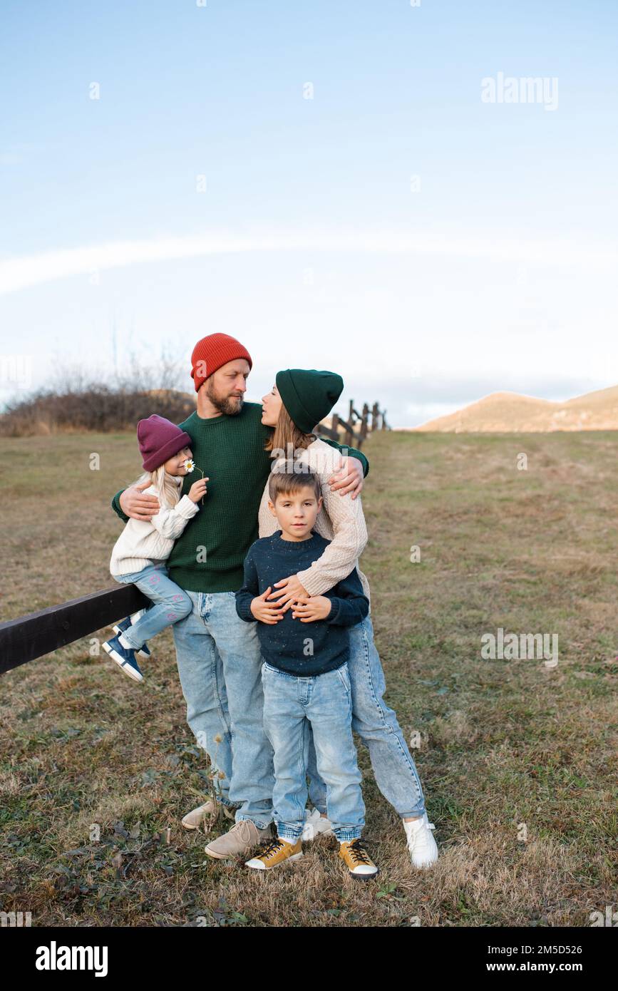 Felice famiglia di padre e madre con i bambini su sfondo autunno natura a scena rustica. Paternità. Foto Stock