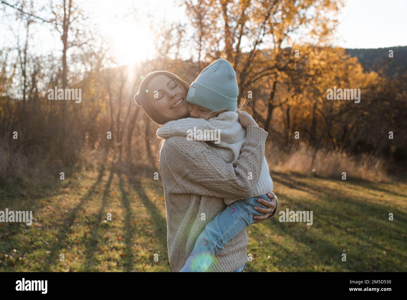 Sorridente madre felice che tiene la bambina piccola ragazza indossare abiti casual nel parco autunnale all'aperto. Contenuti per la famiglia. Maternità. Foto Stock