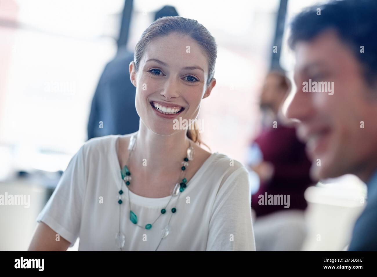 Il successo porta un sorriso. Ritratto di una donna d'affari sorridente seduta in ufficio con i suoi colleghi. Foto Stock