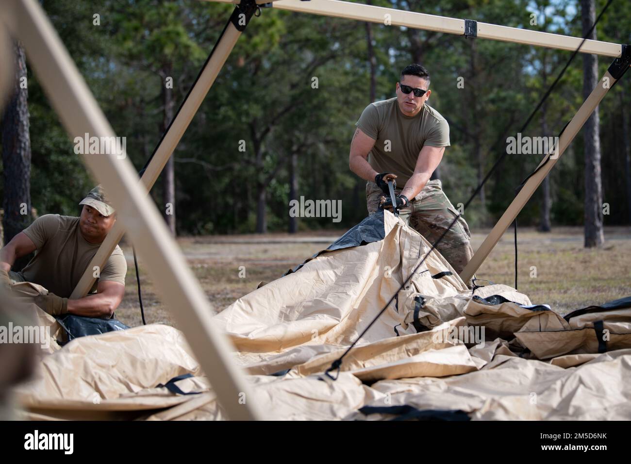 STATI UNITI Air Force Senior Airman Diego CalleCalle, un membro del 1st Special Operations Civil Engineer Squadron Mission Sostainment Team, aiuta a posizionare il top di un sistema di protezione militare durante un addestramento MST 3 marzo 2022, a Hurlburt Field, Florida. I membri della MST sono formati in abilità di spedizione avanzate e sono in grado di svolgere attività al di fuori degli Stati Uniti Specialità dell'aeronautica militare, come fornire rifugio in luoghi austeri. Foto Stock