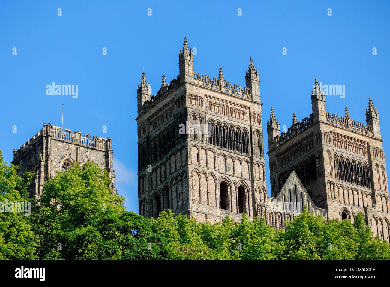 Durham Inghilterra: 2022-06-07: Esterno della cattedrale di Durham durante le giornate estive soleggiate con alberi verdi lussureggianti e cielo blu. Vista in primo piano Foto Stock