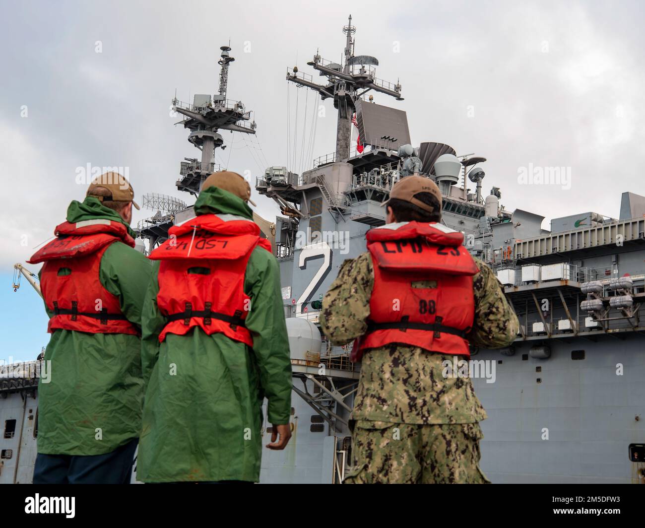 I marinai che servono come linehandlers guardano l'arrivo della nave d'assalto anfibia USS Essex (LHD 2) sul molo. Essex, una parte del Gruppo Essex Amphibious Ready, è tornato alla base navale di San Diego, marzo 4, dopo un dispiegamento negli Stati Uniti 3rd, 5th, e 7th aree Fleet di funzionamento a sostegno della stabilità regionale e di un libero e aperto Indo-Pacifico. Foto Stock