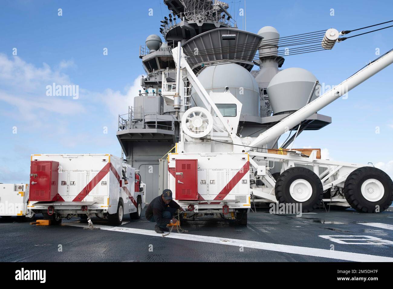 220304-N-VJ326-1011 SAN DIEGO (4 marzo 2022) -- Aviation Boatswain’s Mate 3rd Class Cameron Crawford, di Atlanta, regola una catena di ancoraggio sul ponte di volo a bordo della nave d’assalto anfibia USS Tripoli (LHA 7), marzo 4. Tripoli è una nave d'assalto anfibio di classe americana ospita a San Diego. Foto Stock