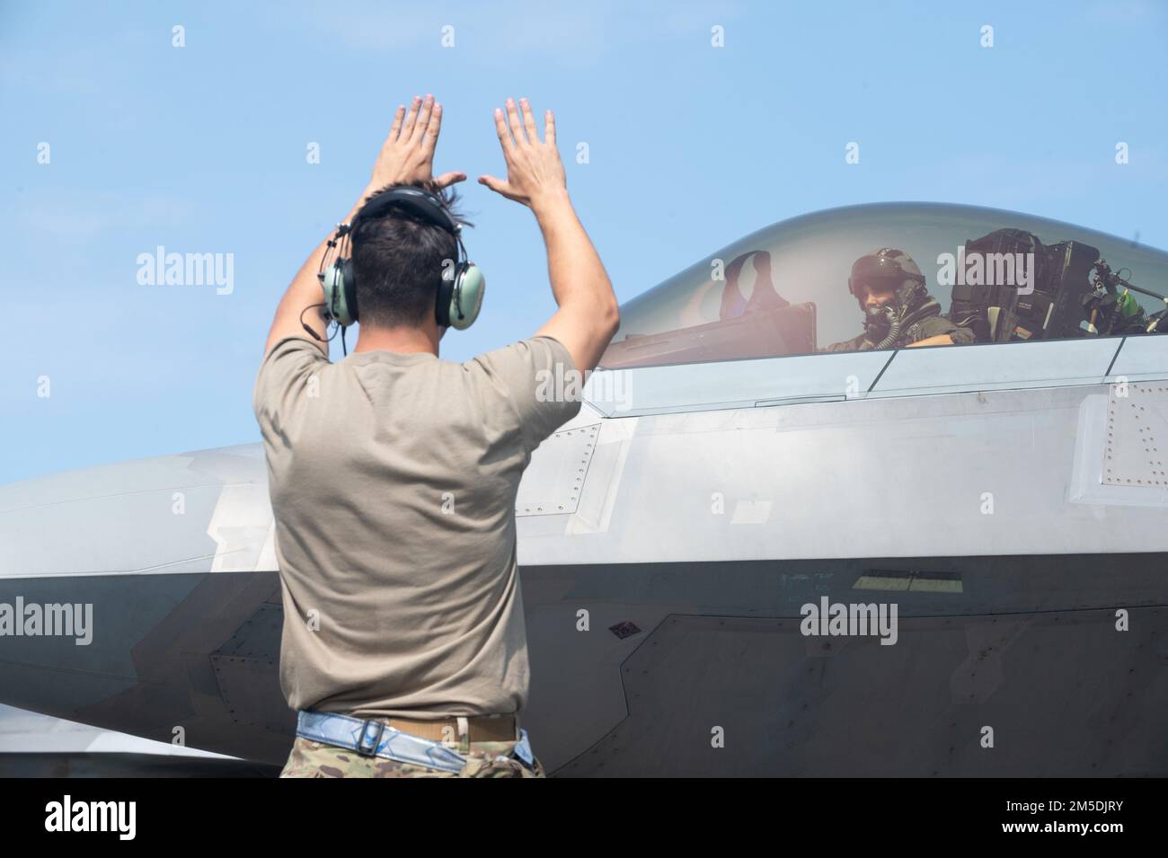 Un Airman multi-capace del 154th Maintenance Group marshalls un F-22 Raptor durante l'esercizio ho`oikaika 4 marzo 2022, all'aeroporto internazionale di Hilo, Hawaii. Ho`oikaika è stata condotta da Total Force Airmen della Guardia Nazionale dell'Hawaii Air, del Nevada ANG e dalle loro controparti attive della 15th Wing e della 354th Fighter Wing. L'esercizio è stato un'opportunità per le unità partner di dimostrare e migliorare la loro capacità di implementare e operare rapidamente in sedi remote. Foto Stock