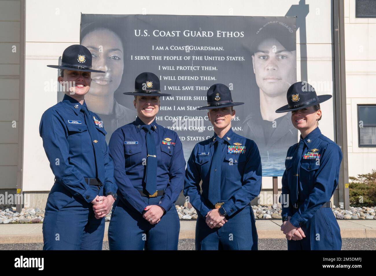 Petty Officer 2nd Class Caleigh Vazquez (a sinistra), Petty Officer 1st Class Elena Cappelmann (a sinistra al centro), Chief Petty Officer Tiffany Moore (a destra al centro), E Petty Officer 2nd Class Kerrigan King (a destra) formano una squadra di comandante di un'azienda tutta femminile prima di raccogliere la società di reclutamento Yankee-201 per iniziare le loro otto settimane di formazione di reclutamento, 4 marzo 2022. Al Training Center Cape May, siamo guidati dai valori fondamentali della Guardia Costiera: Onore, rispetto e devozione al dovere. Foto Stock