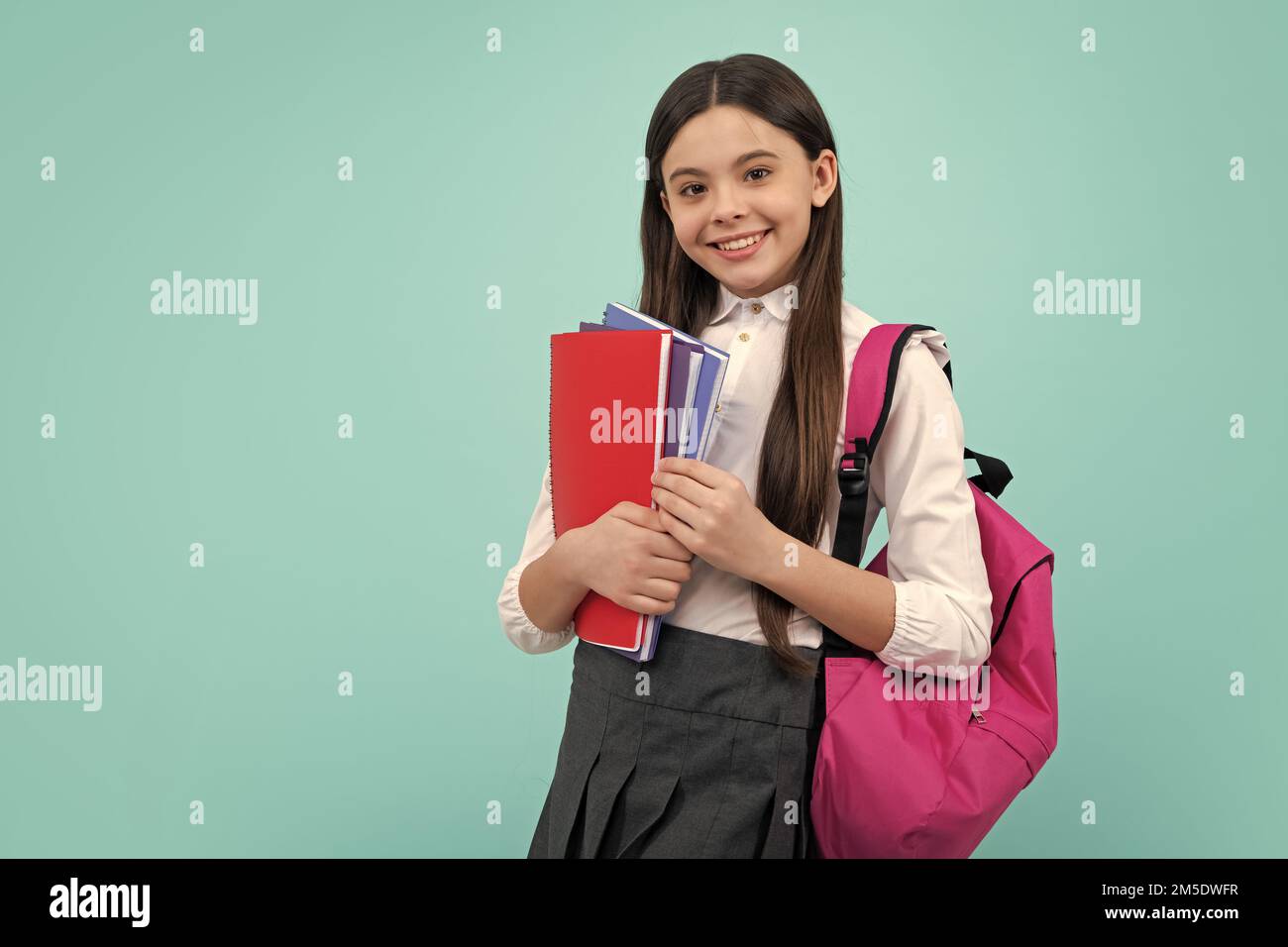 Schoolchild, studentessa adolescente con zaino scuola tenere libro su sfondo blu isolato studio. Scuola per bambini e concetto di istruzione. Foto Stock