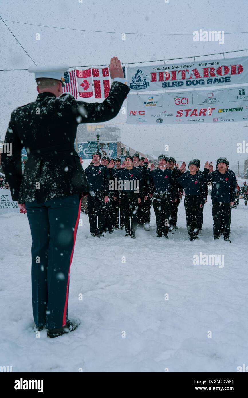 STATI UNITI Matthew Krempel, l'ufficiale comandante per la stazione di reclutamento Portland, emette il giuramento di arruolamento ai poolee con l'Anchorage di substatina di reclutamento e Wasilla alla corsa di cani da slitta di pista di Iditarod 2022 in Anchorage, Alaska il 5 marzo 2022. I Marines hanno avuto l'opportunità di condurre una cerimonia di giuramento sotto la bandiera di inizio ed istruiscono gli spettatori circa le occasioni che il corpo marino ha da offrire. L'Iditarod è una gara annuale in Alaska che si estende per oltre 900 chilometri, partendo da Anchorage e terminando a Nome. Foto Stock