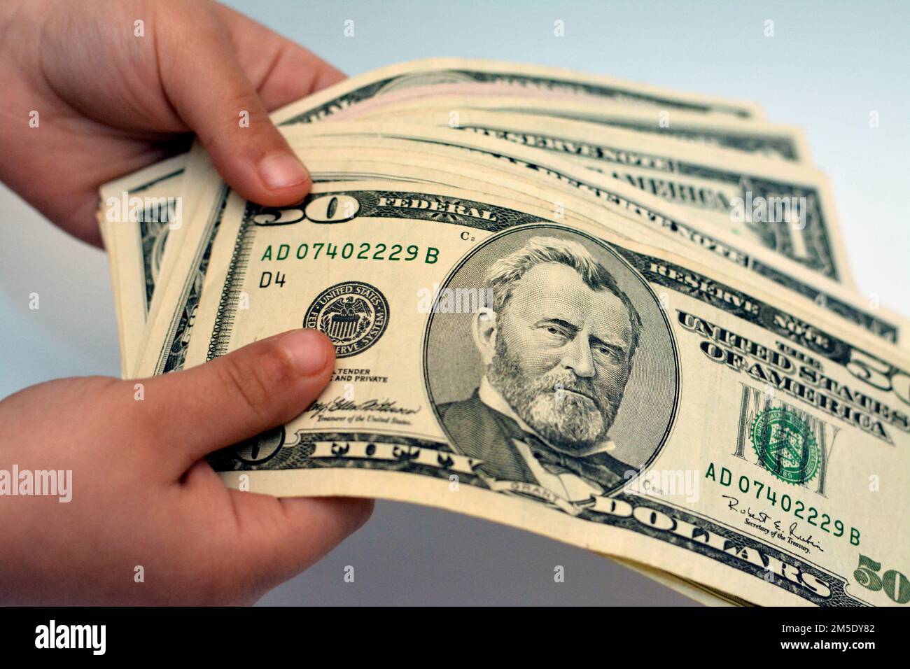 Fifty $50 dollari americani banconote in mano di un bambino caratteristiche profilo il 18th presidente degli Stati Uniti, Ulysses S. Grant, Economic and fi Foto Stock