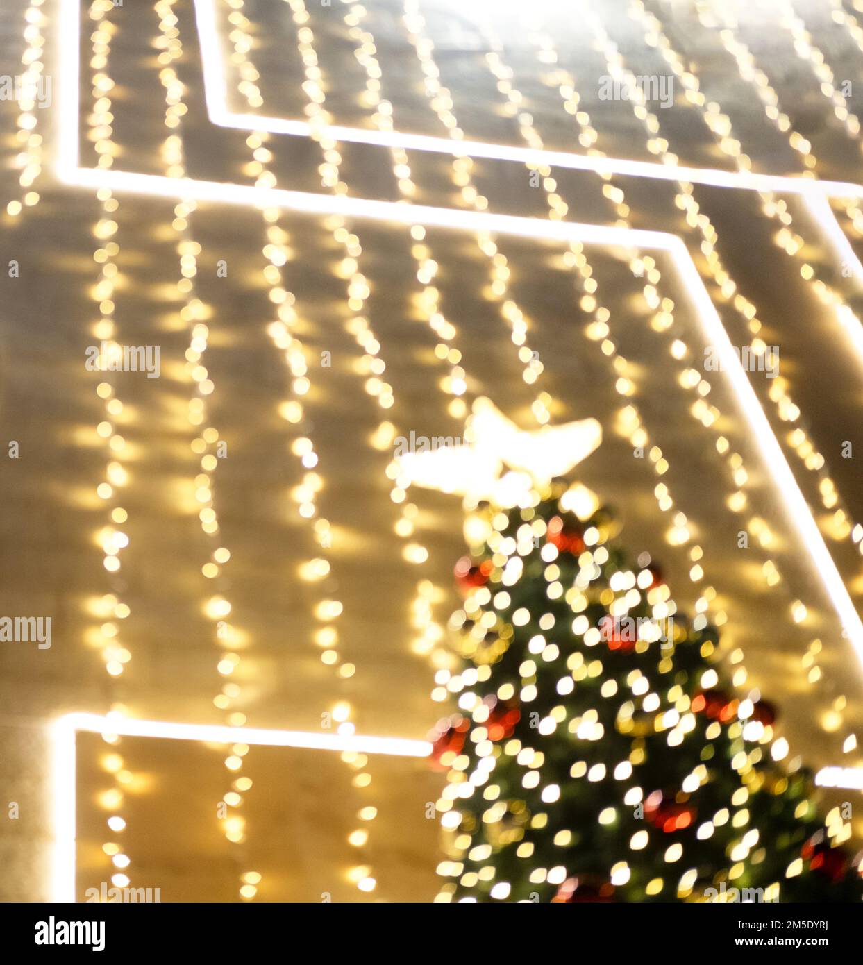 Le luci dei ghirlande sull'albero di Natale con le sfere rosse sono fuori fuoco. Foto Stock