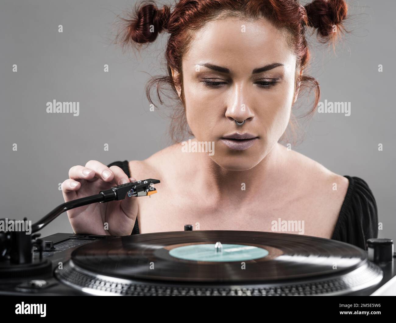 Bella donna che sta per mettere l'ago giù sul disco in vinile che gira sul suo giocatore di registrazione. Foto Stock