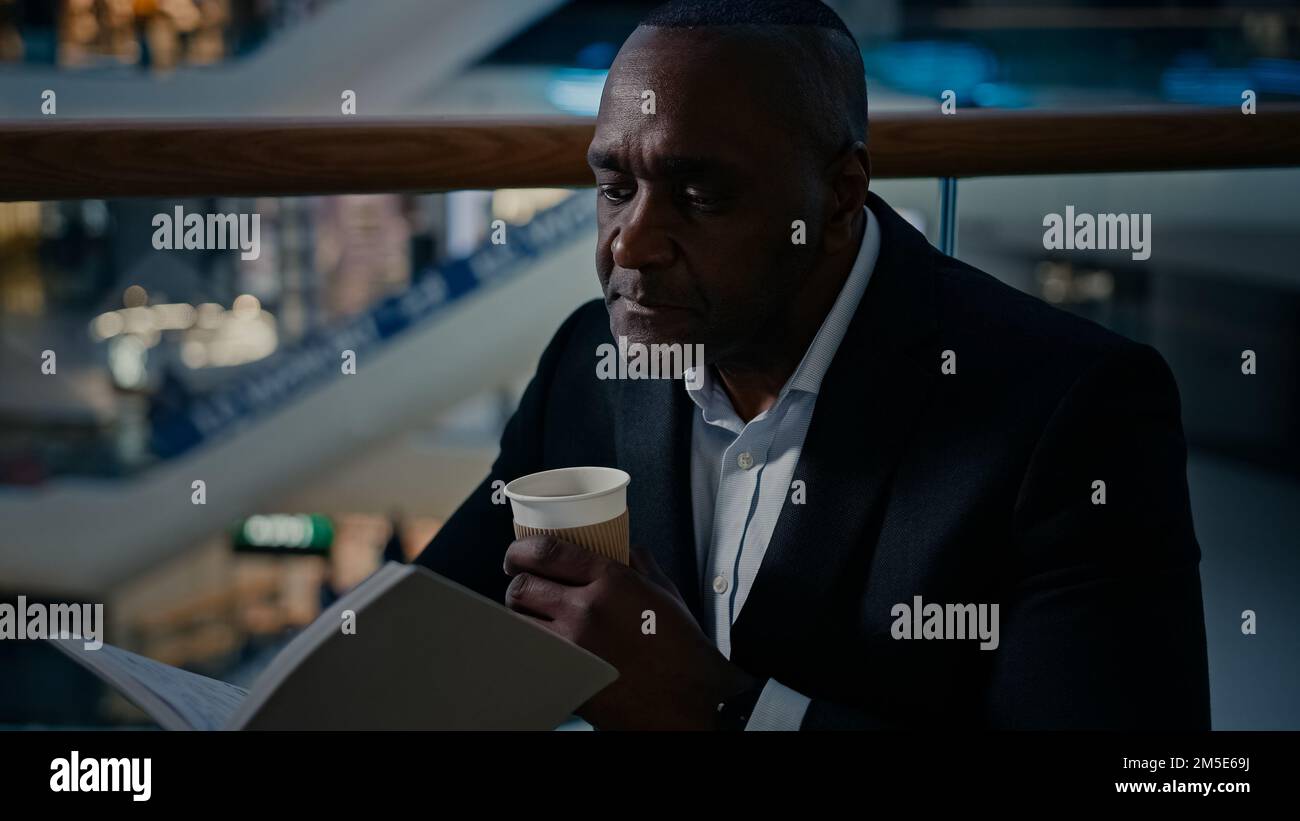 Etnico uomo africano uomo d'affari datore di lavoro imprenditore bere tè caffè caldo aromatico a tavola in caffetteria ristorante bere latte Foto Stock