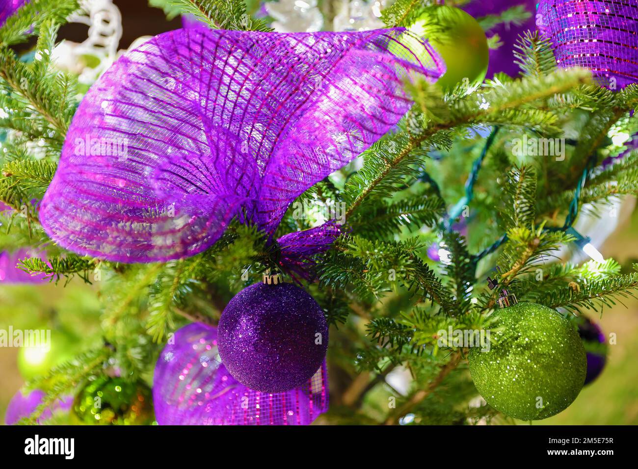 Primo piano di ornamenti su un albero di Natale con luci e altre decorazioni. Foto Stock